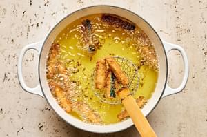 battered zucchini spears being deep fried in vegetable oil