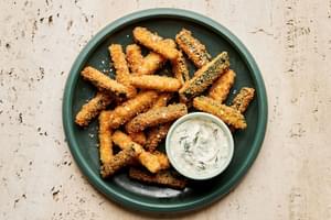 Golden-brown, extra crispy fried zucchini sticks sprinkled with flaky salt served with a side of creamy dill dip.