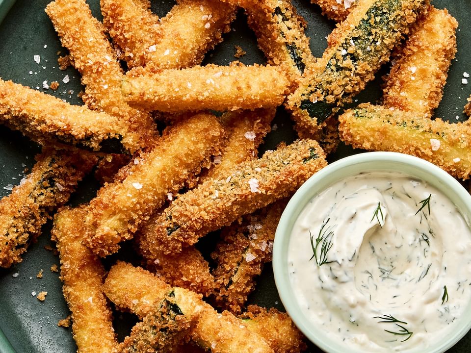 Golden-brown, extra crispy fried zucchini sticks sprinkled with flaky salt served with a side of creamy dill dip.