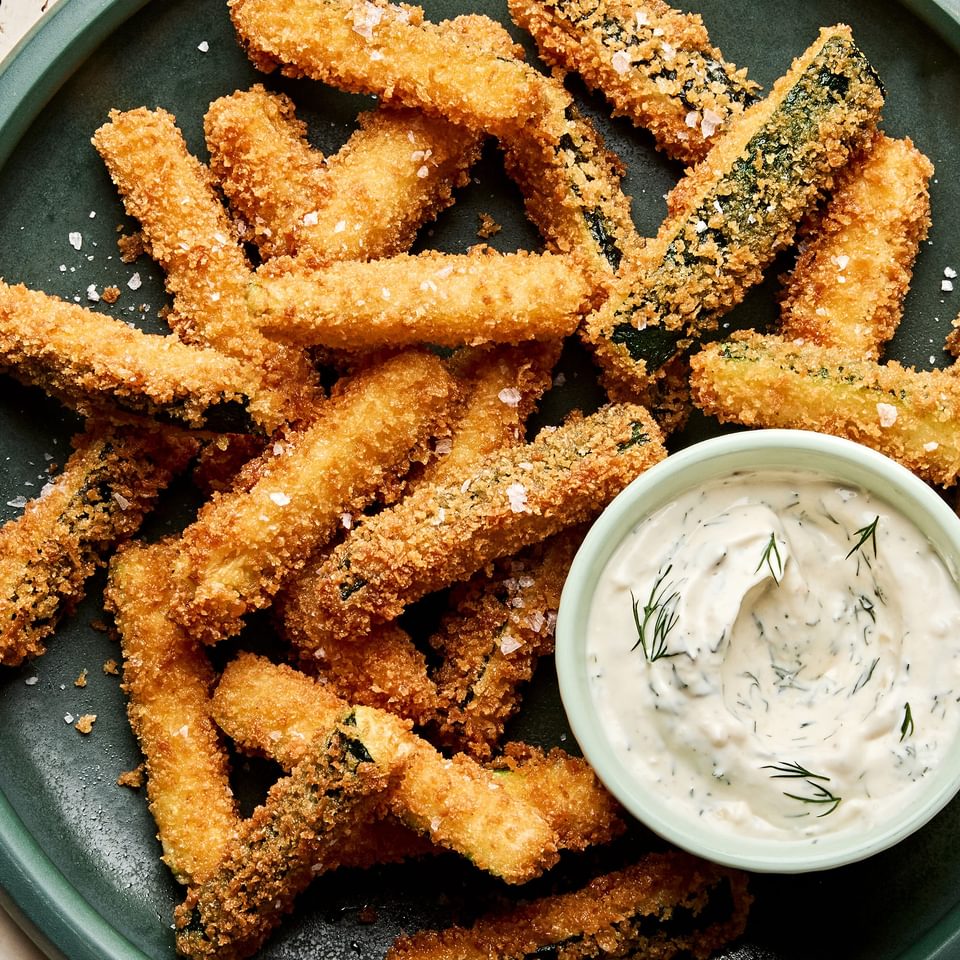 Golden-brown, extra crispy fried zucchini sticks sprinkled with flaky salt served with a side of creamy dill dip.