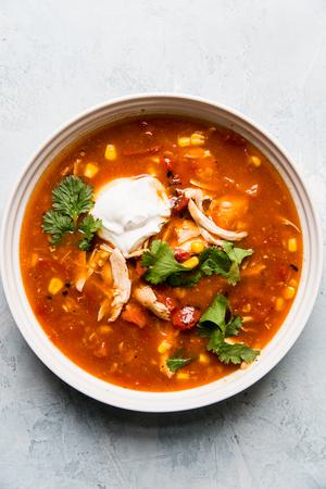 5 ingredient chicken tortilla soup in a bowl with cilantro and sour cream