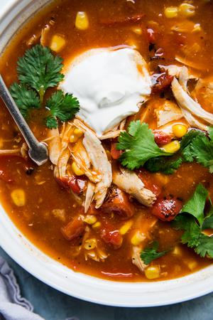 5 ingredient chicken tortilla soup in a bowl with cilantro and sour cream