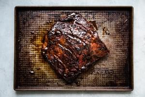 grilled flank steak marinated in hoisin sauce and Chinese five spice on a baking sheet