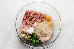 Ingredients laid out for chicken teriyaki meatballs eggs, salt, bread crumbs, garlic in a bowl