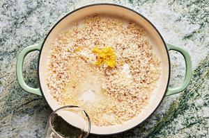butter, shallots, arborio rice and garlic being cooked in a dutch oven