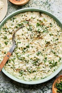 homemade herb risotto in a bowl with a serving spoon made with butter, parmesan and lemon