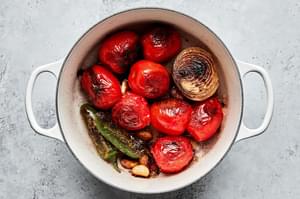 tomatoes, jalapeños, white onion and garlic being charred in a skillet