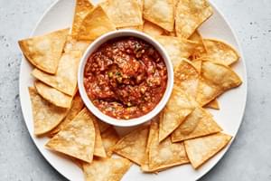 a bowl of homemade salsa surrounded by tortilla chips