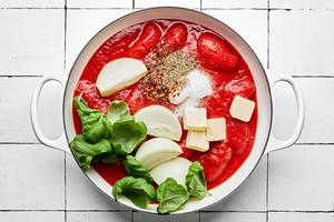 san marzano tomatoes, basil, onion, spices, butter & red pepper flakes cooking in a pot to make spicy tomato sauce