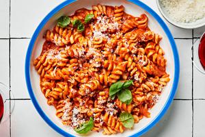 a bowl of Fussili Pasta with Spicy Tomato Sauce topped with parmesan cheese and basil leaves
