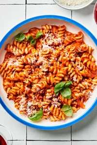 a bowl of Fussili Pasta with Spicy Tomato Sauce topped with parmesan cheese and basil leaves