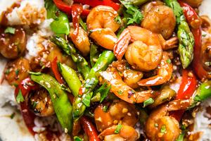 Garlic Shrimp Stir Fry with snow peas and bell peppers over rice on a plate