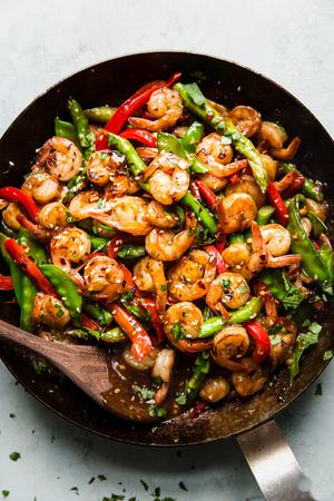 Garlic Shrimp Stir Fry in a an with a wooden spoon