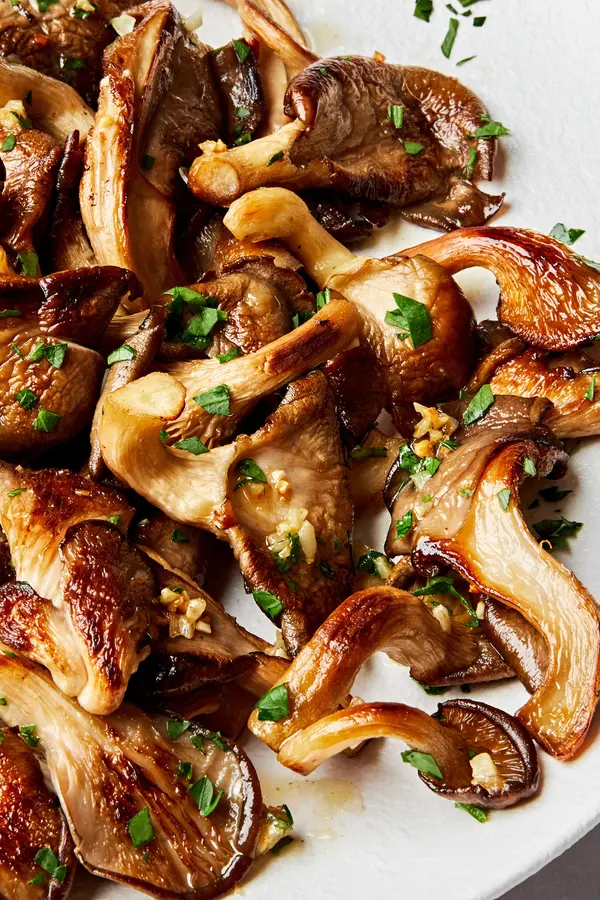 a plate of garlic butter oyster mushrooms cooked in salt, olive oil, butter, garlic and sprinkled with fresh parsley
