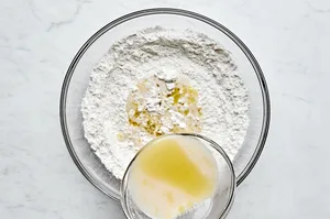 yeast mixture being poured into a bowl of gluten free flour and salt