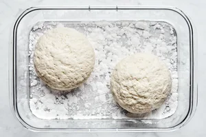 2 gluten free pizza dough balls sprinkled with gluten free flour