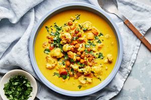 a bowl of homemade golden soup made with carrots, chickpeas, cauliflower, turmeric, ginger and coconut milk