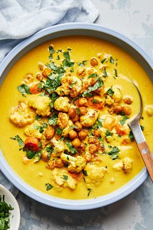 a bowl of homemade golden soup made with carrots, chickpeas, cauliflower, turmeric, ginger and coconut milk