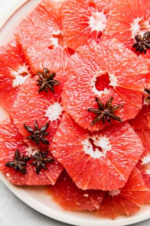slices of red grapefruit on a plate with star anise simple syrup