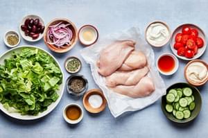 4 raw chicken breasts, romaine, tomatoes, cucumber, red onion, kalamata olives & ingredients for greek dressing in prep bowls