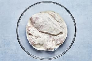 raw chicken breast marinating in olive oil, mayo, Greek yogurt, vinegar, garlic powder, oregano, basil, sea salt and pepper