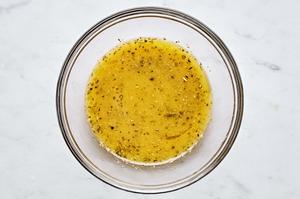 homemade greek salad dressing in a bowl made with vinegar, lemon juice, garlic, mustard, salt, oregano and pepper