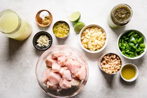 Ingredients laid out for Green Chicken Chili Soup with chicken stock, onions, green bell peppers, salsa, garlic and beans