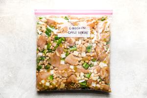 Ingredients in a freezer bag for Green Chicken Chili Soup with chicken stock, onions, bell peppers salsa, garlic and beans
