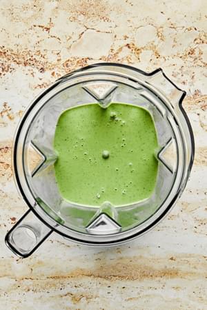 green goddess dressing in a blender made with goat cheese, olive oil, fresh herbs, fish sauce, lemon juice, pepper & salt