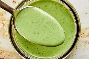 homemade green goddess dressing in a glass jar being scooped with a spoon