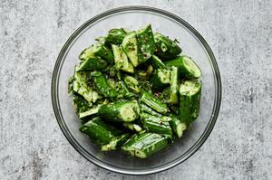 smashed cucumber salad in a glass bowl made with green onions, cilantro, and lime juice