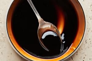 Balsamic reduction in a pot with a spoon. Made with balsamic vinegar, sugar, salt and cornstarch
