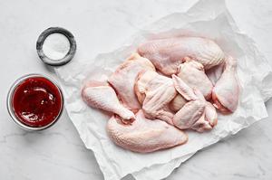3 pounds bone-in, skin-on chicken wings, legs, thighs and breasts on parchment paper next to bowls of salt and bbq sauce