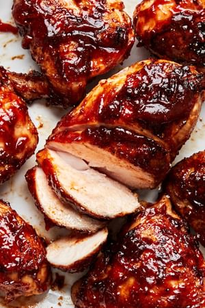 grilled bbq chicken sliced on a serving tray and smothered in bbq sauce