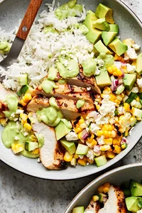 Grilled Chicken Bowl with corn and zucchini salad served on top of white rice in a bowl with a fork