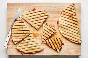 grilled chicken quesadillas being sliced on a wooden cutting board