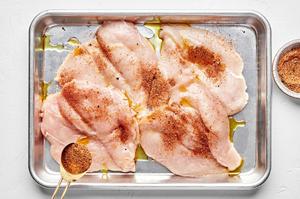 raw chicken being seasoned with taco seasoning
