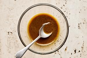 olive oil, curry powder, salt, and pepper being stirred together in a glass bowl