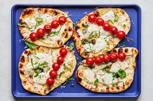 grilled flatbread with burrata cheese topped with fresh basil grilled tomato skewers