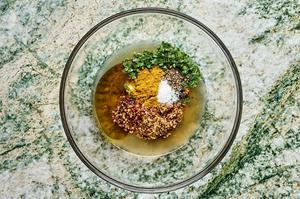 honey, mustard, olive oil, lemon juice, cilantro, garlic, curry powder, salt, pepper, and red pepper being combined in a bowl