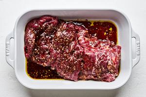 skirt steak being marinated in soy sauce, garlic, salt, pepper and red pepper flakes