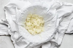 grated onion being strained in cheesecloth. until the moisture is drained