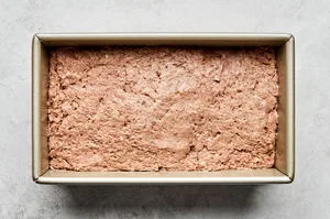 gyro meat made with beef, lamb, onion and spices pressed into a loaf pan ready to be baked