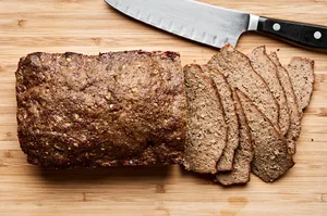 juicy homemade gyro meat made with lamb and beef being sliced on a cutting board