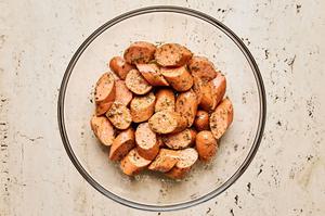sliced Italian sausage being tossed with thyme, granulated garlic, cumin, oregano, pepper, salt, and olive oil