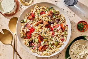 gyro pasta salad with sausage, olives, parsley, red onion, feta cheese, tomatoes & cucumbers in a Greek yogurt dressing