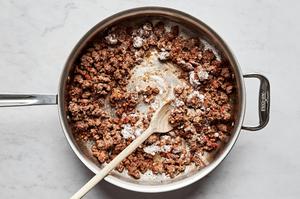 butter and flour being added to a pan with ground beef and spices