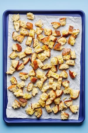 torn rustic bread tossed in olive oil, Italian seasoning, garlic powder & salt on a parchment lined baking sheet