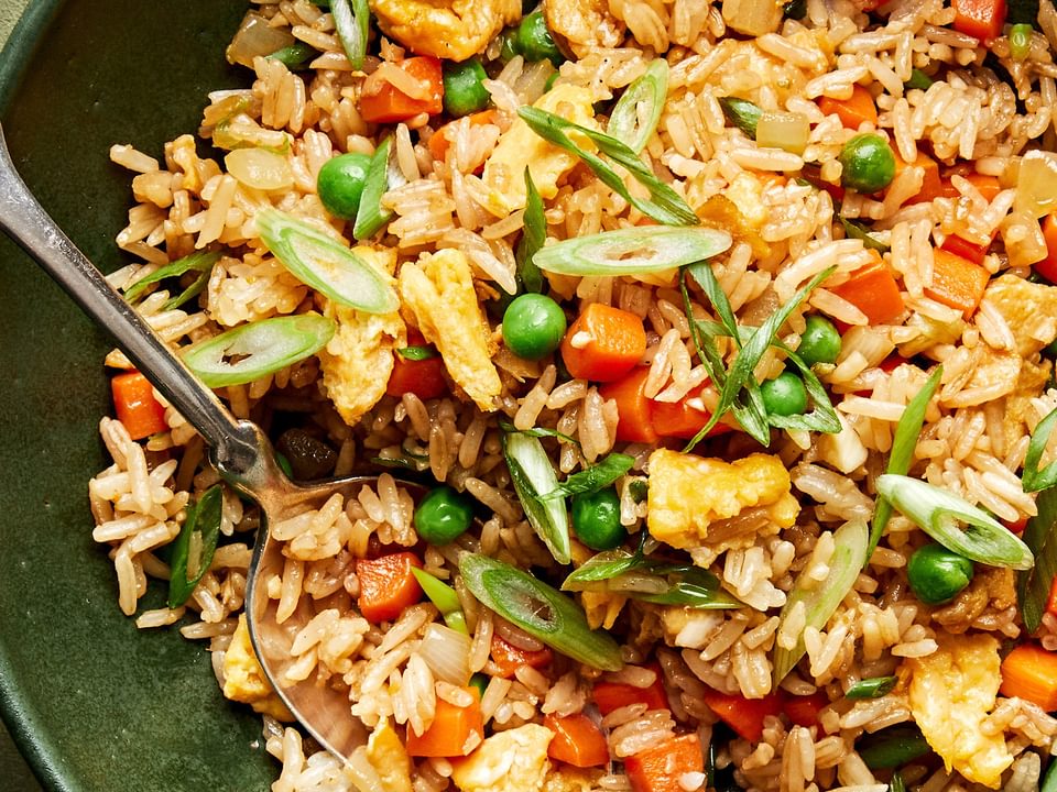 A bowl of homemade fried rice with  scrambled egg, vegetables, and green onions tossed with coconut aminos and soy sauce