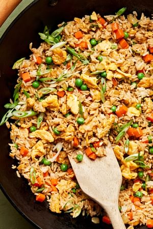 A wok of homemade fried rice with scrambled egg, vegetables, and green onions tossed with coconut aminos and soy sauce